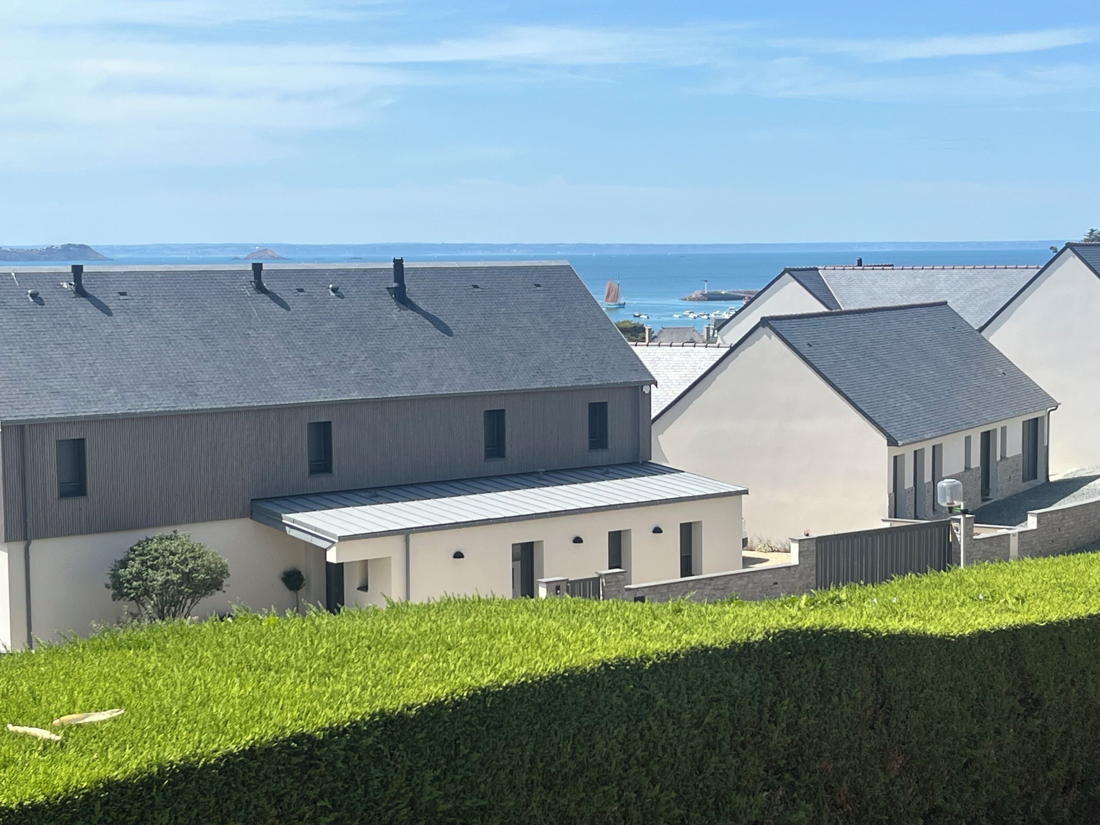 A modern building with a flat roof, a small attached structure, and a well-maintained hedge.