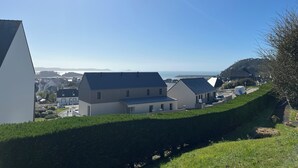 A residential area with modern houses, a clear sky, and a distant view of the sea. - Beautiful view of the port and the Verdelet. Garden level. Wifi   (Erquy)