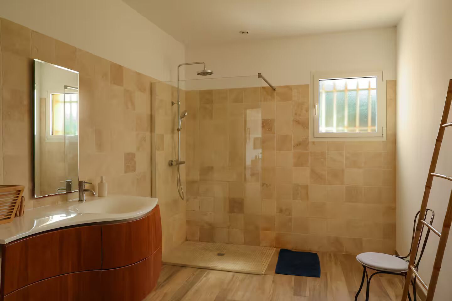 Un baño con ducha, lavamanos, espejo y ventana.