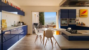 A modern kitchen with blue cabinetry, a dining area with a view, and a 'Presse' sign on the wall.