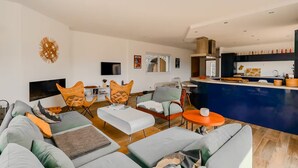 A modern living room with a sofa set, a coffee table, and a kitchen area with a bar counter.