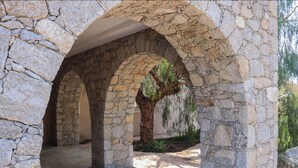 A stone archway leading to a covered outdoor area with a tree in the center.
