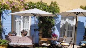 A pool area with a blue-tiled edge, a white umbrella, and a seating arrangement with a table and chairs.