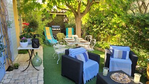 An outdoor patio with wicker furniture, a grill, and a table set for dining.