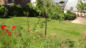A grassy garden with red poppies and pink flowers, a brick building, and a view of the sea. - Modern house with garden and beautiful sea view (Pléneuf-Val-André)