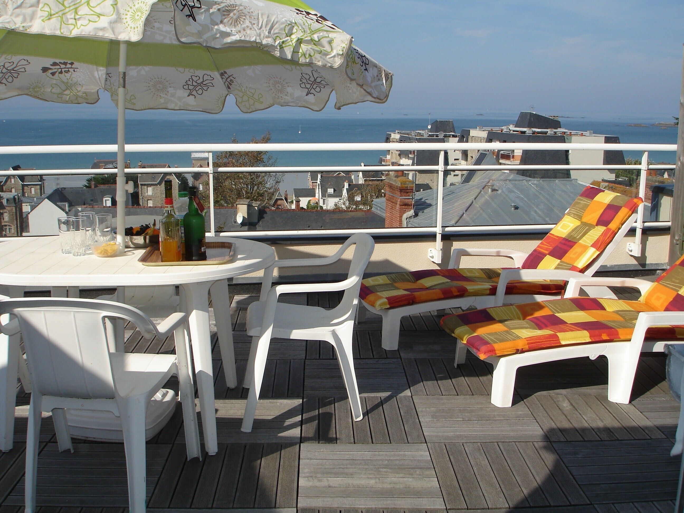 A deck with a table, chairs, and a colorful lounge chair.