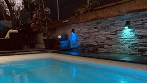 Een binnenzwembad met een stenen muur en een waterattractie met blauwe verlichting.