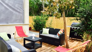 Een terras met buitenmeubilair, waaronder een bank, stoelen en een tafel.
