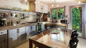 Una cocina moderna con una isla central, electrodomésticos de acero inoxidable y un comedor con mesa y sillas de vidrio.