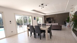 A spacious dining area with a table and chairs, a sofa, and a TV.