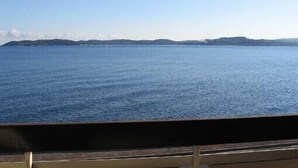 Une vue sur une mer calme, avec des reliefs lointains sous un ciel dégagé.