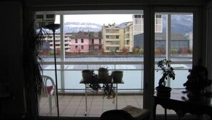 A room with a large window, a chair, a small table, and potted plants. - App. 93m2 bright calm tt comfort, terrace, garage, hyper-center, close station (Annecy)