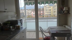 A kitchen with a dining area, a view of buildings, and a balcony. - App. 93m2 bright calm tt comfort, terrace, garage, hyper-center, close station (Annecy)