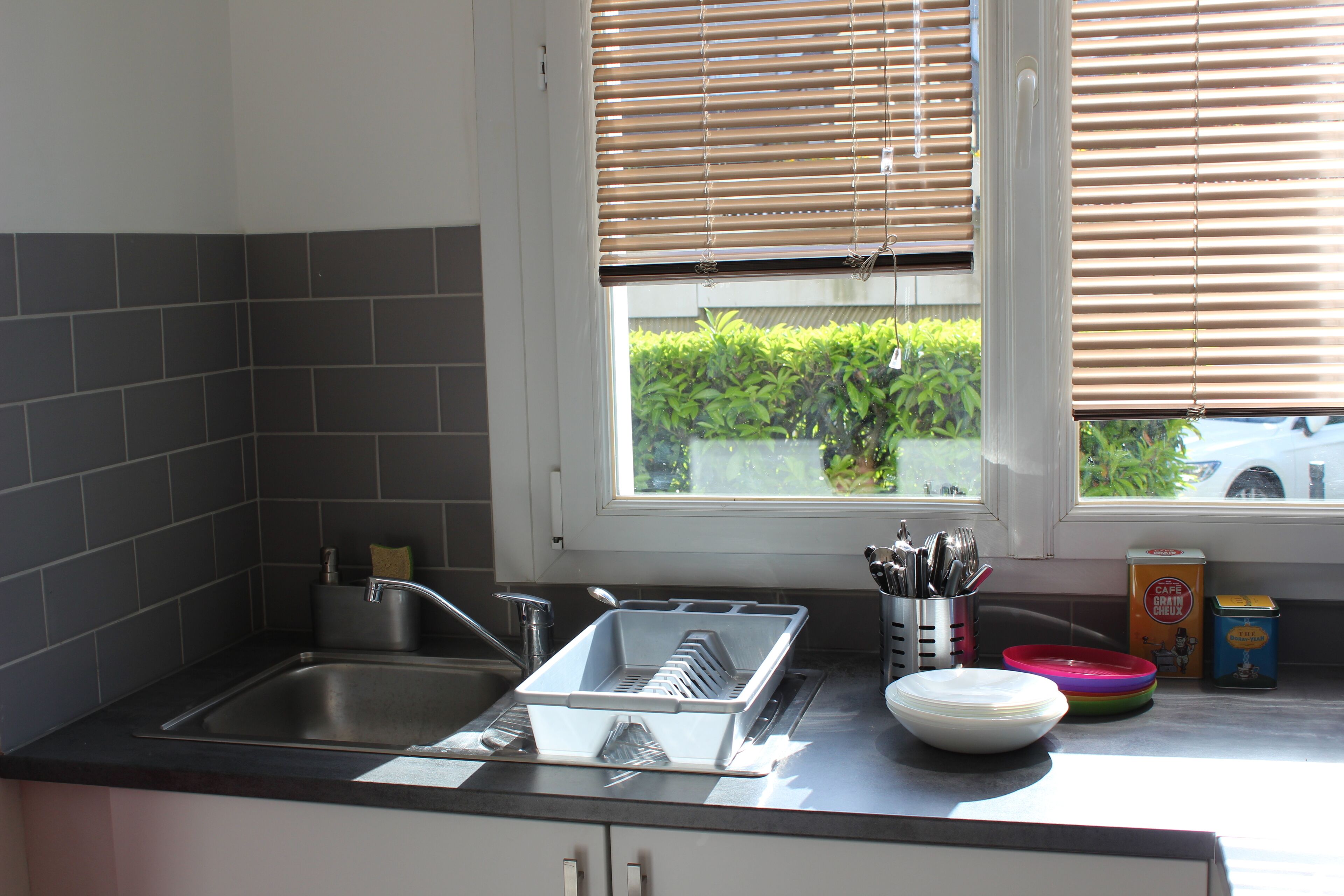 Una cocina con un lavabo, escurreplatos y diversos utensilios de cocina.