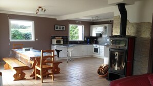 Een ruime keuken met een eethoek, een open haard en grote ramen.