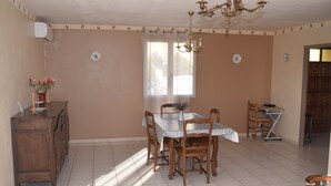 A dining area with a table, chairs, a chandelier, and a wooden cabinet.