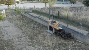 A fenced outdoor area with a bench, a lamp post, and a tennis court in the background.