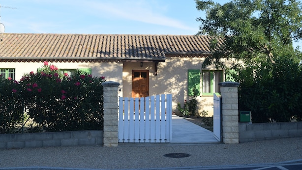 A house with a tiled roof, a wooden door, and a white picket fence.