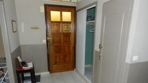 A hallway with a wooden door, a tiled floor, and a small table with books.