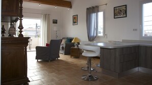 A modern kitchen with a central island, a dining area with a table and chairs, and a living room with a sofa and a lamp. - Superb new T3 apartment in the heart of Sanary, 100m from the port, 2 minutes on foot,  (Sanary-Sur-Mer)