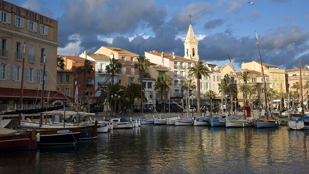 A marina with boats docked, a prominent church tower, and buildings with balconies. - Superb new T3 apartment in the heart of Sanary, 100m from the port, 2 minutes on foot,  (Sanary-Sur-Mer)
