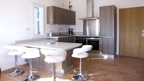 A modern kitchen with a central island, bar stools, and built-in appliances. - Superb new T3 apartment in the heart of Sanary, 100m from the port, 2 minutes on foot,  (Sanary-Sur-Mer)
