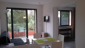 A room with a dining table, chairs, a television, and a sliding glass door leading to an outdoor area.