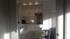 A compact kitchen with white cabinets, a built-in microwave, a coffee maker, and a sink.