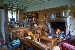 A cozy living room with leather sofas, a fireplace, a bookshelf, and a bar area with various bottles and glasses. - Charming house in the heart of Vexin (55 minutes from Paris) (Château-Sur-Epte)