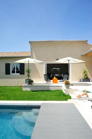 Uma área à beira da piscina com um terraço, assentos externos e vista para a piscina.