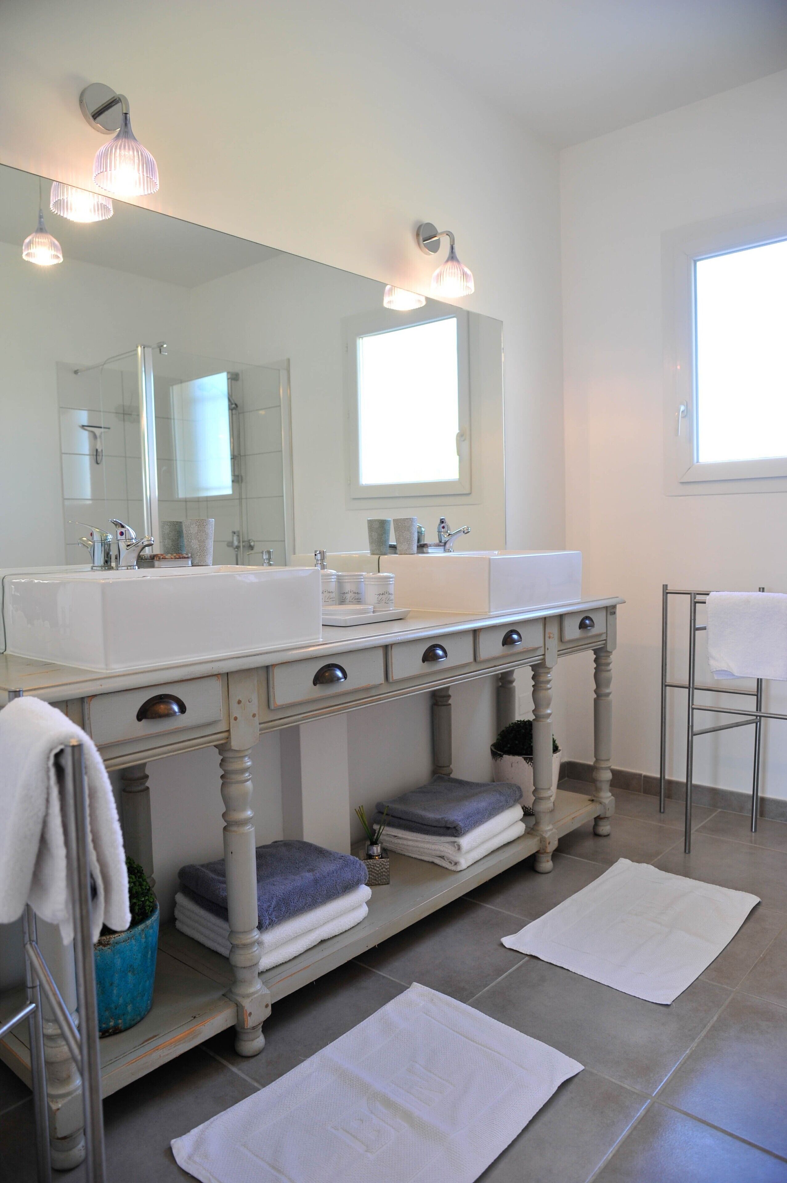 Une salle de bain avec un double lavabo, un grand miroir et un porte-serviettes.