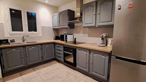 Una cocina moderna con armarios grises, un refrigerador de acero inoxidable, un microondas y una cafetera.