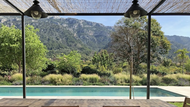 Un área de estar al aire libre cubierta con piscina y vistas a la montaña.