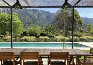 A covered outdoor seating area with a pool and mountain views. - Stone villa with mountain views, quiet and close to the city center (Soller)