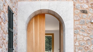 Un edificio de paredes de piedra con puerta de madera y entrada arqueada.