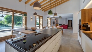Una cocina moderna con una isla grande, iluminación colgante y vistas al exterior.
