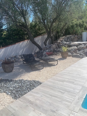 A patio area with a wooden deck, lounge chairs, and a barbecue grill.