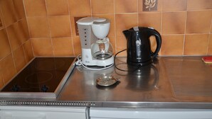 A kitchen with a coffee maker, a kettle, and a dishwasher.