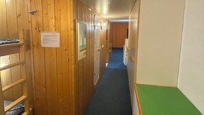Een smalle gang met houten wanden en een stapelbed aan de linkerkant.