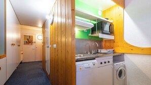 Een kleine keuken met een magnetron, fornuis en wasmachine.