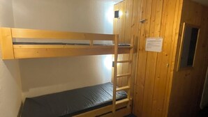 Een slaapkamer met een stapelbed, houten wanden en een deur.