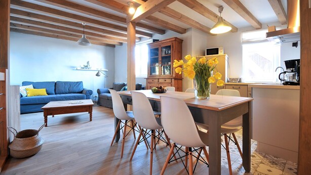 A modern living space with a dining area, kitchen, and a blue sofa.