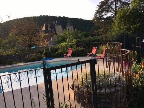 Relax by the serene pool surrounded by lush greenery and a scenic hillside.