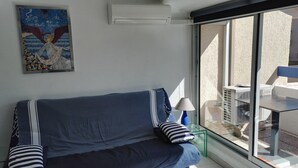 Un divano blu con cuscini a righe, una lampada e un quadro appeso al muro.
