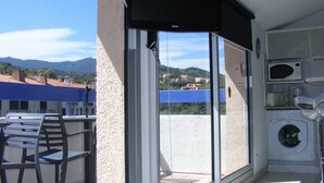 Un balcone con vista su un paesaggio montuoso, una lavatrice e una sedia.