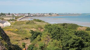 A coastal town with a beach, houses, and a lighthouse in the distance.