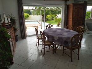 A dining area with a table covered in a purple tablecloth, surrounded by wooden chairs.