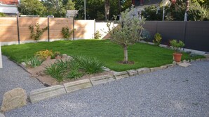 A well-maintained garden with a variety of plants and a small tree, surrounded by a wooden fence and a gravel path. - Quimiac Villa by the sea, close to all shops (Mesquer)