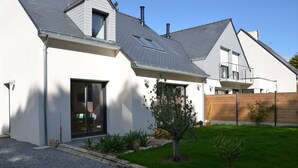 A modern house with a sloped roof, a large sliding glass door, and a small tree in the front yard. - Quimiac Villa by the sea, close to all shops (Mesquer)