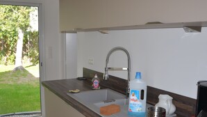 A kitchen with a sink, a dish soap bottle, a coffee maker, and a red tray. - Quimiac Villa by the sea, close to all shops (Mesquer)